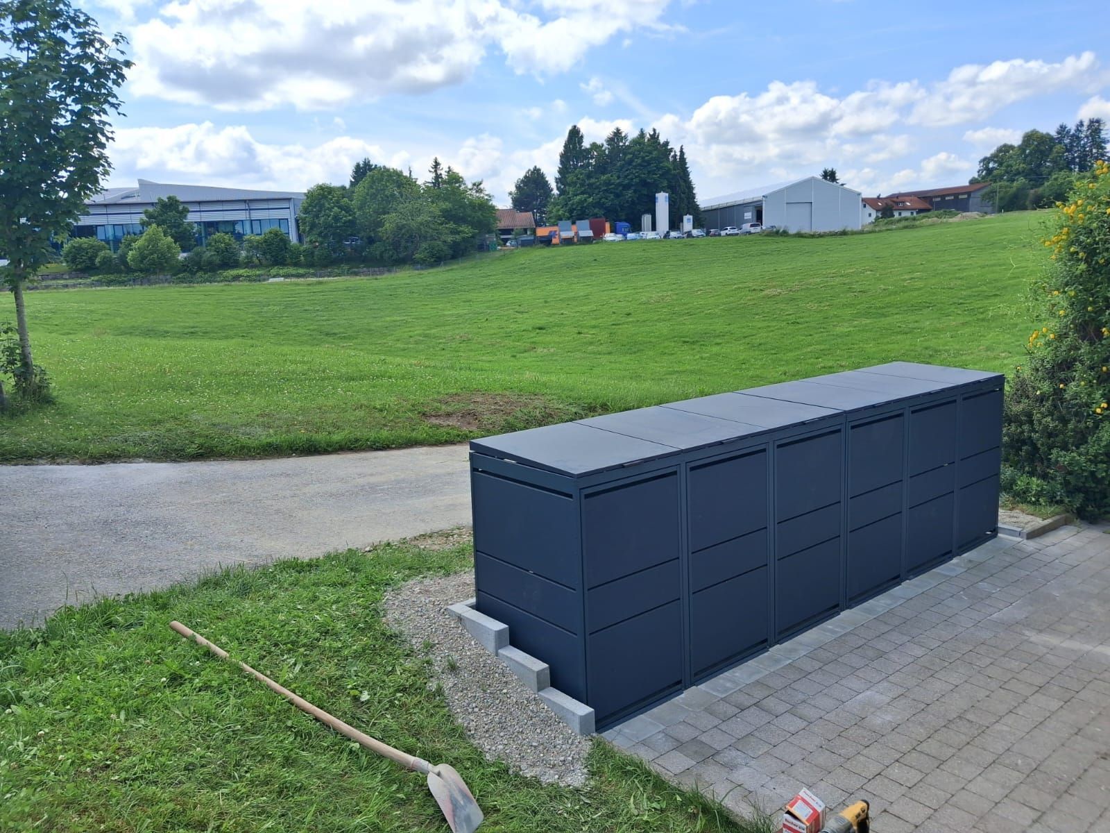 Dunkle Paketbox auf Pflasterweg mit Wiese im Hintergrund