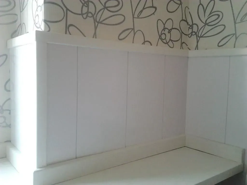 Paredes paneladas blancas con mostrador integrado y fondo de papel pintado floral.