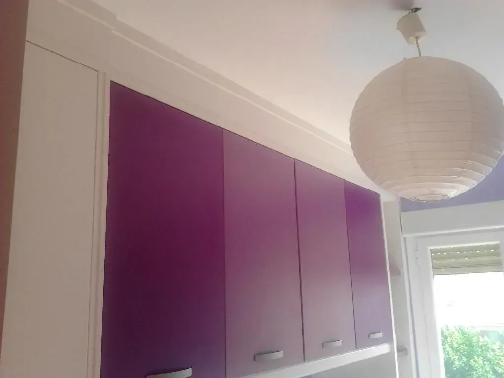Armarios morados con detalles blancos y una lámpara de papel colgando del techo.