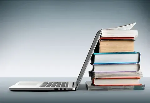 Una computadora portátil está junto a una pila de libros.