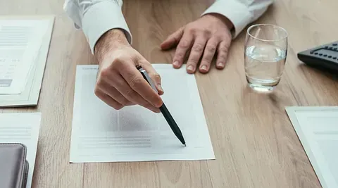 Un hombre está escribiendo en un trozo de papel con un bolígrafo.
