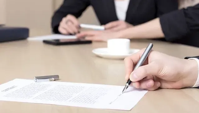 Una persona está escribiendo en un trozo de papel con un bolígrafo.