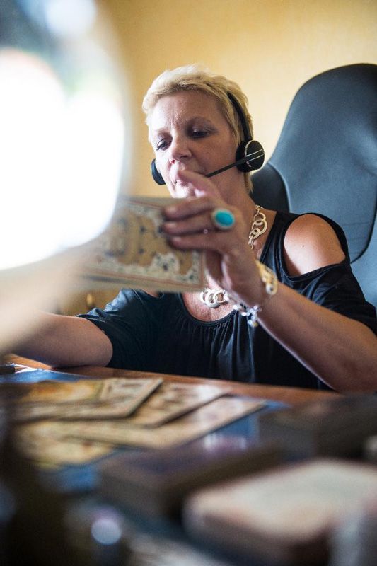 Une femme portant un casque audio manipule de l'argent liquide sur une table où des billets sont étalés au premier plan.