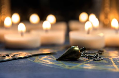 Collier pendentif sur un tissu bleu à motifs, avec une douce lumière de bougie floue en arrière-plan
