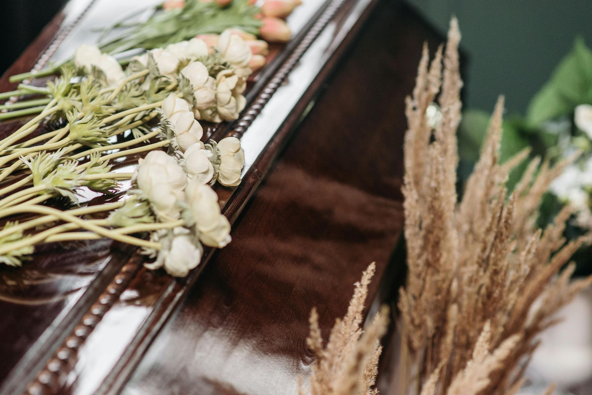 Des fleurs séchées et de la verdure décoratives disposées à côté d'une surface en bois foncé