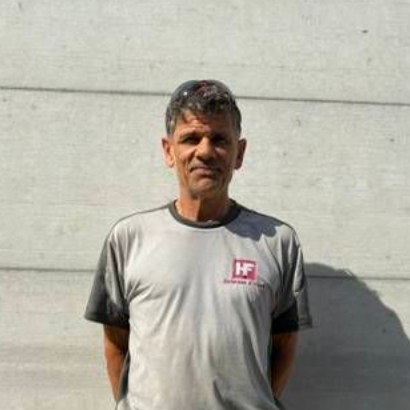 Ein Mann, der an einer Betonwand steht, trägt ein graues T-Shirt und Shorts.