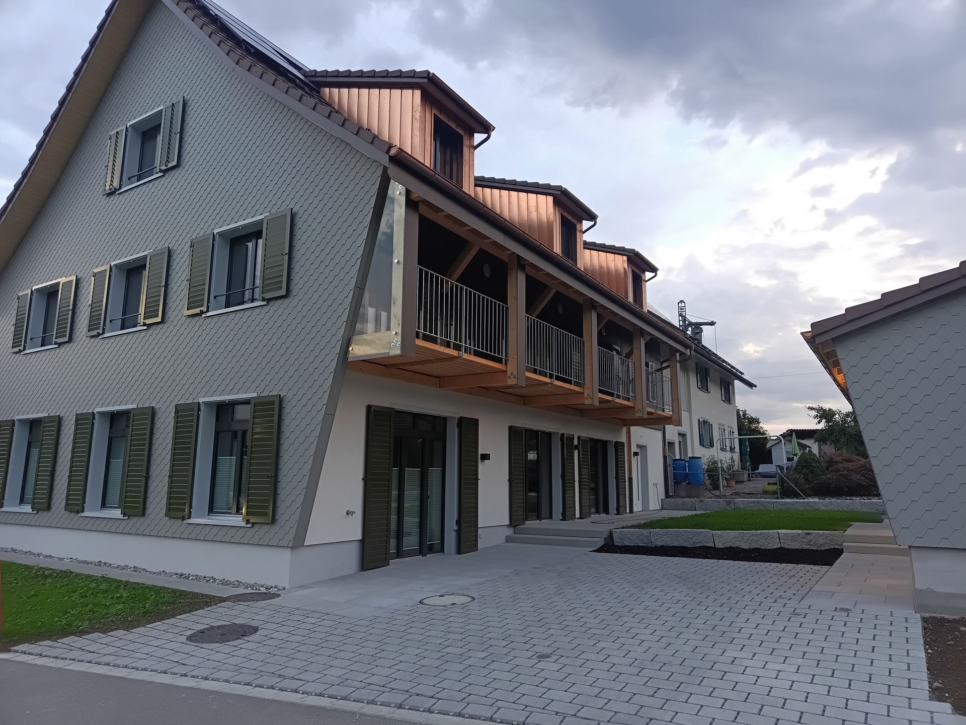 Moderne Apartmentgebäude entlang eines gepflasterten Innenhofs unter bewölktem Himmel
