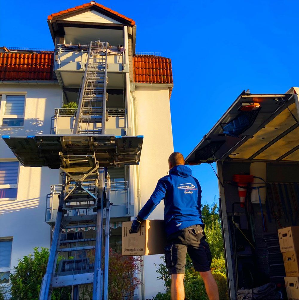 Mitarbeiter unseren Umzugsunternehmens in Hildesheim trägt Kiste zum Stecklift für Transport in obere Stockwerke.