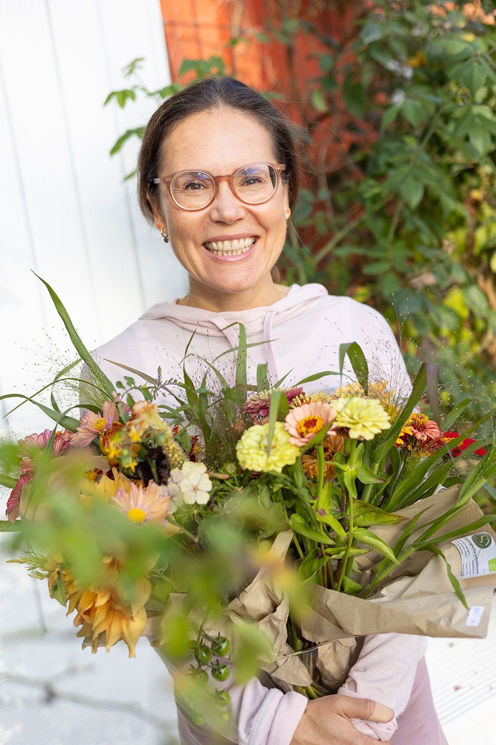 Lächelnde Frau mit einem bunten Blumenstrauß im Freien.
