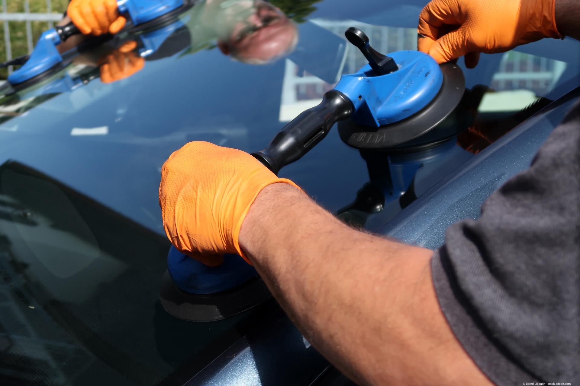 zwei Männer bringen eine neue Windschutzscheibe an einen Wagen an