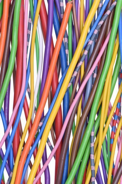 Una densa maraña vertical de coloridos cables eléctricos en tonos rojos, azules, verdes, amarillos, naranjas y morados.
