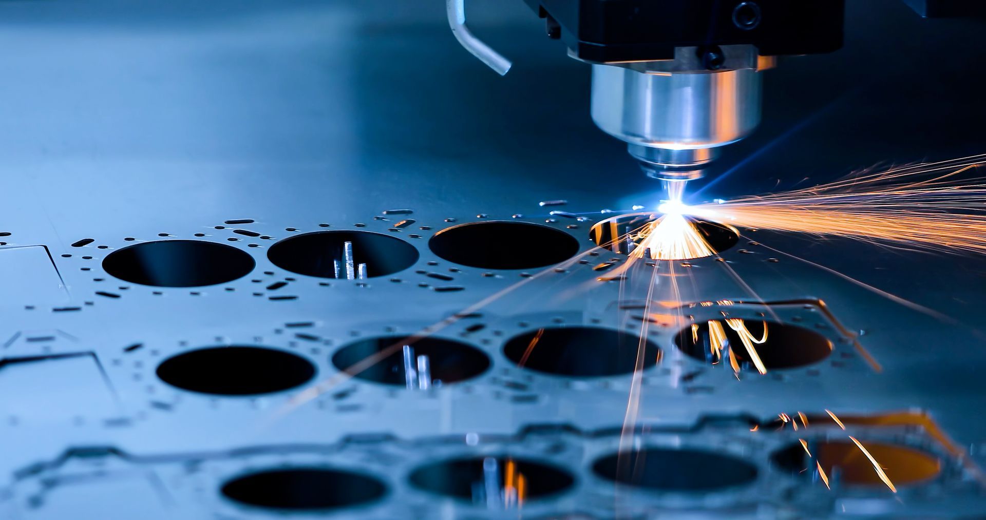 Laserschneider im Einsatz, der durch ein Metallblech schneidet, Funken sprühen in einer Werkstattumgebung.