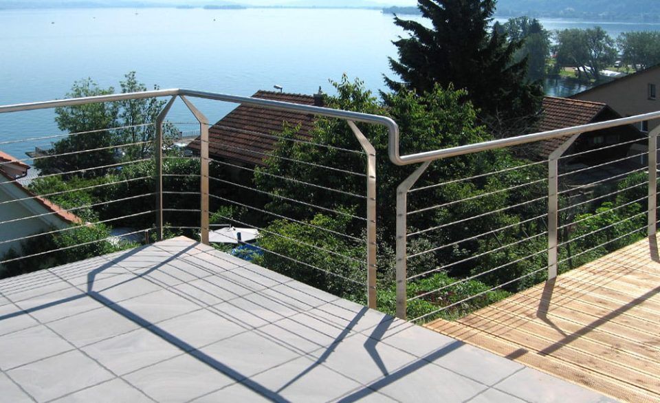 Edelstahlseilgeländer auf einer Terrasse mit Blick aufs Wasser.