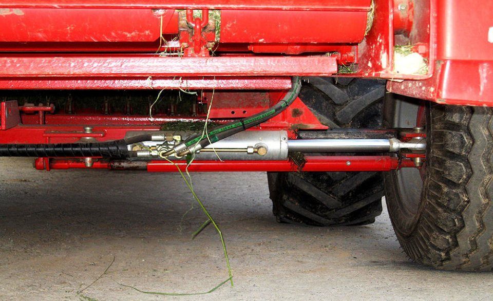 Roter landwirtschaftlicher Anhänger mit Hydraulikzylinder und Reifen.