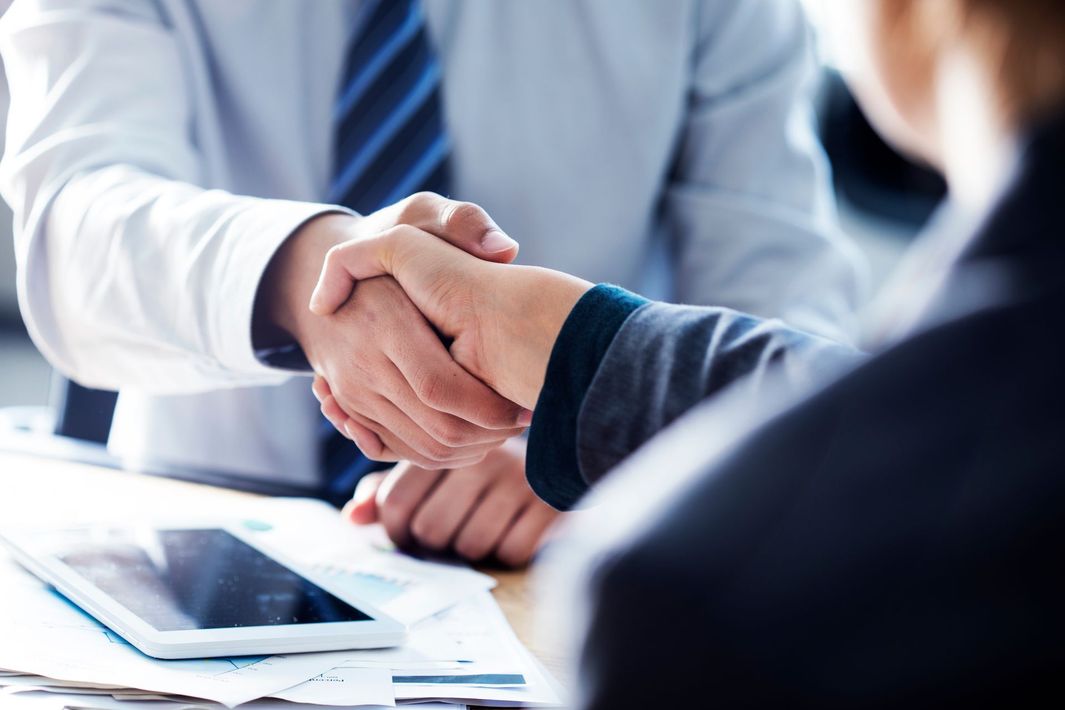 Poignée de main entre deux professionnels autour d’une table