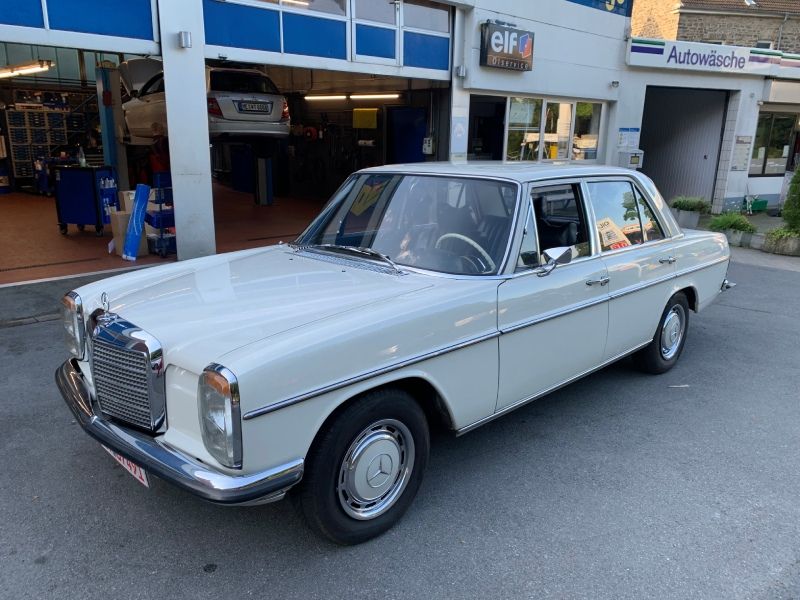 Klassische silberne Mercedes-Limousine, geparkt vor einer Autowerkstatt