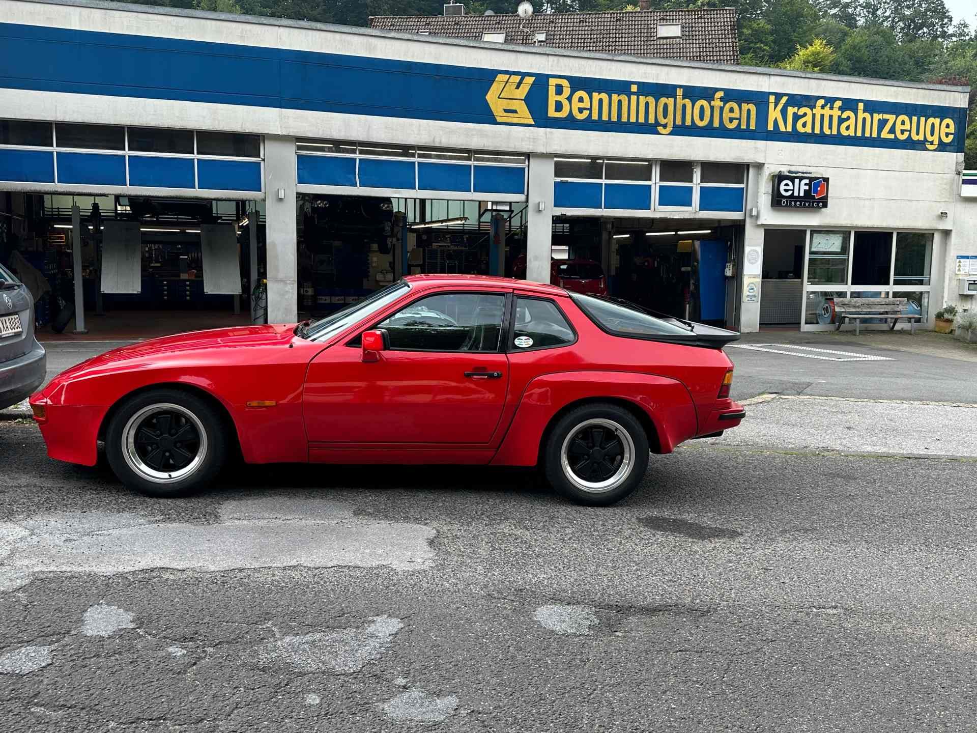 Ein roter Oldtimer-Sportwagen parkt vor einem Autohaus in Bennighofen.