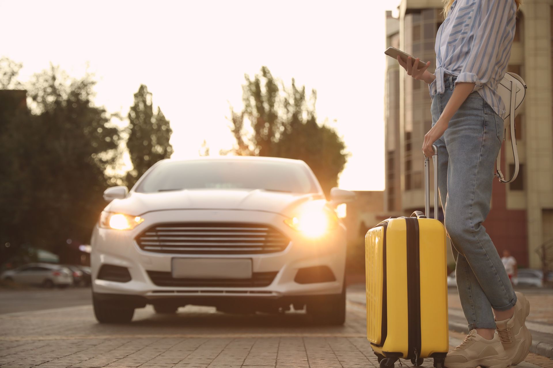 Person mit Reisekoffer vor einem Taxi