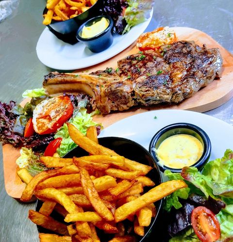 Dîner steak : steak grillé sur une planche en bois, frites, salade et sauce.