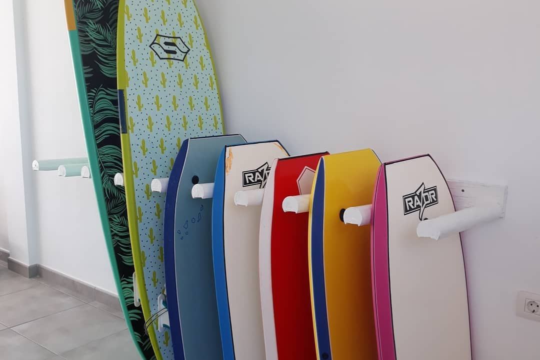 Un montón de tablas de surf están alineadas en una pared.