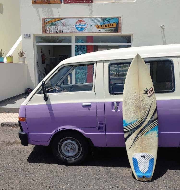 Una mujer sostiene una tabla de surf en el océano.
