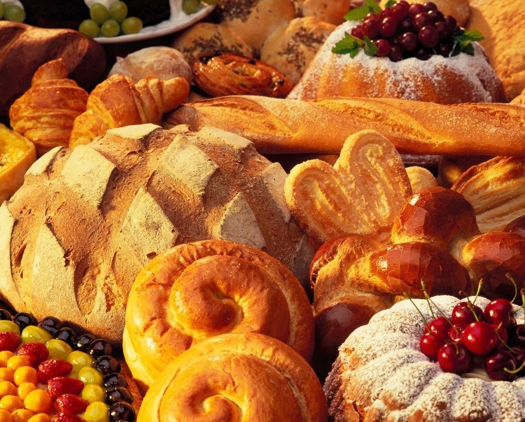Un montón de diferentes tipos de pan y pasteles en una mesa.