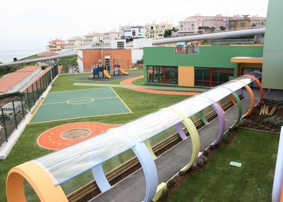 Um parque infantil colorido e uma passarela com quadra esportiva, escorregadores e áreas gramadas