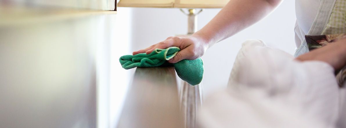 Person wischt Oberfläche ab mit grünem Microfasertuch