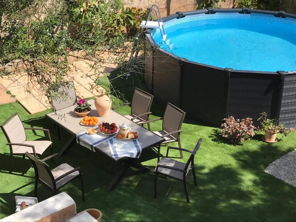 Patio trasero con mesa, sillas, comida y una piscina azul elevada en la esquina.