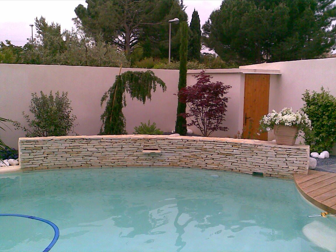 Un bassin et des plantes derrière un muret