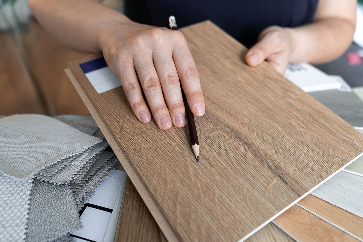 Personne qui montre la couche de revêtement d'une planche de parquet