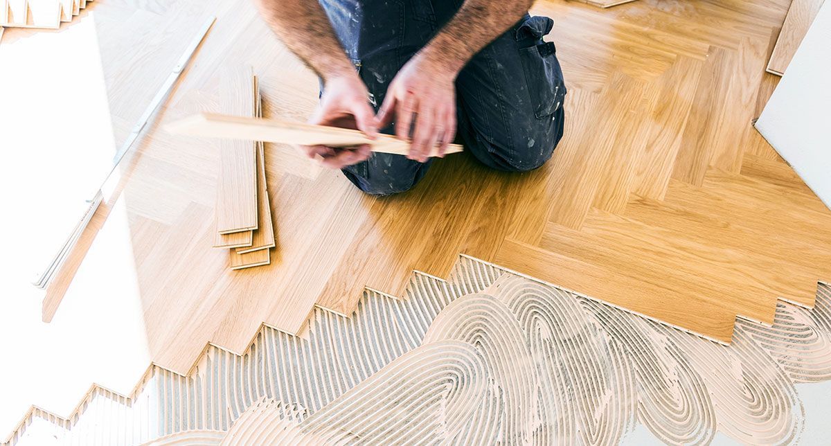 Ouvrier qui installe du parquet en chêne à chevrons