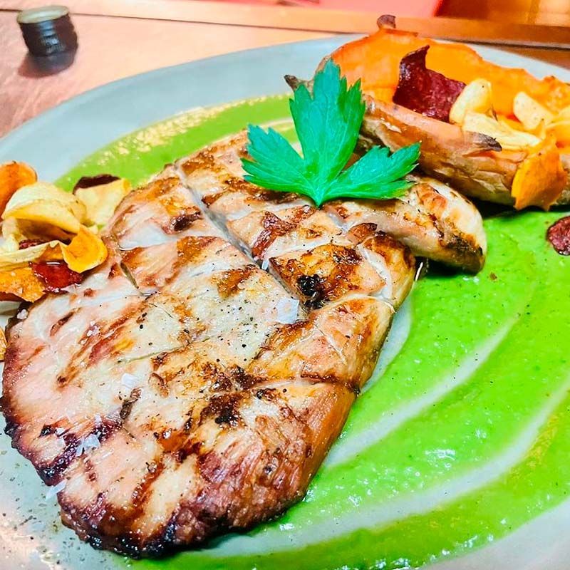 Un primer plano de un plato de comida con carne y verduras sobre una mesa.