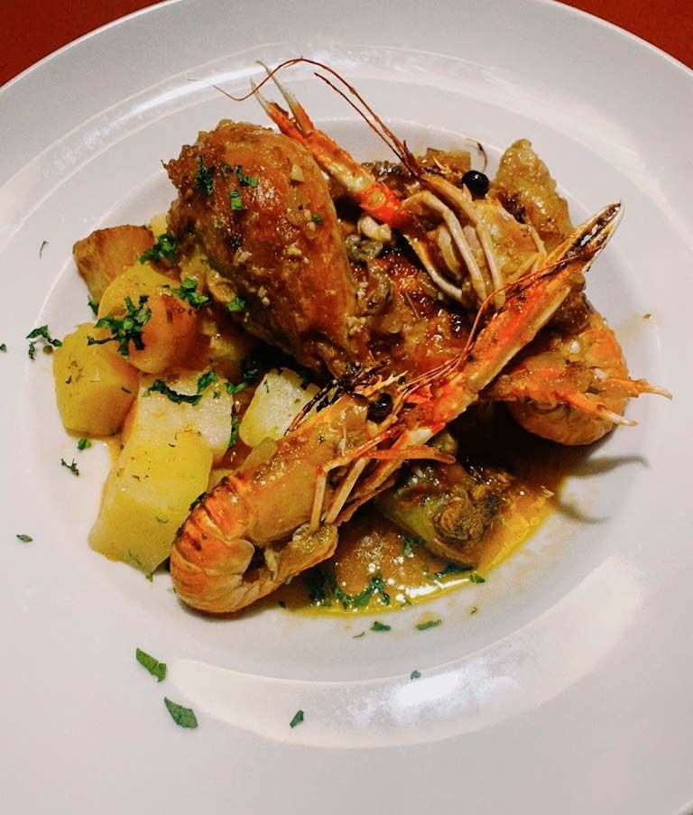 Un plato blanco cubierto con camarones y papas.