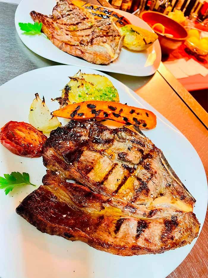 Un plato blanco con un filete y verduras sobre una mesa.