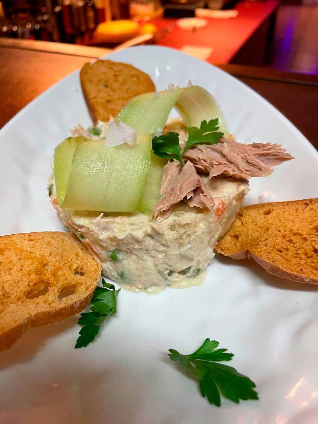 Un plato blanco cubierto con ensalada y pan sobre una mesa.