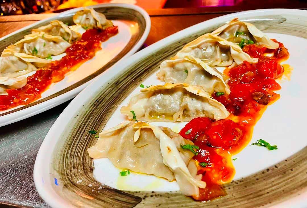 Sobre una mesa hay dos platos de comida con salsa encima.