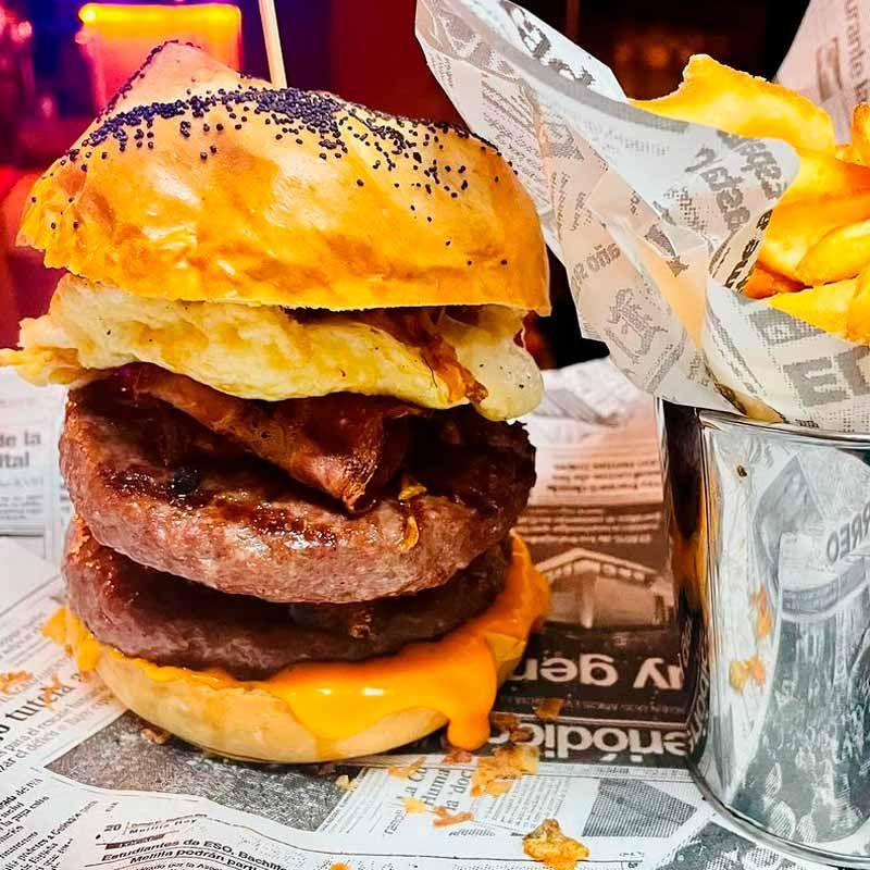 Una hamburguesa y unas patatas fritas están envueltas en papel de periódico.