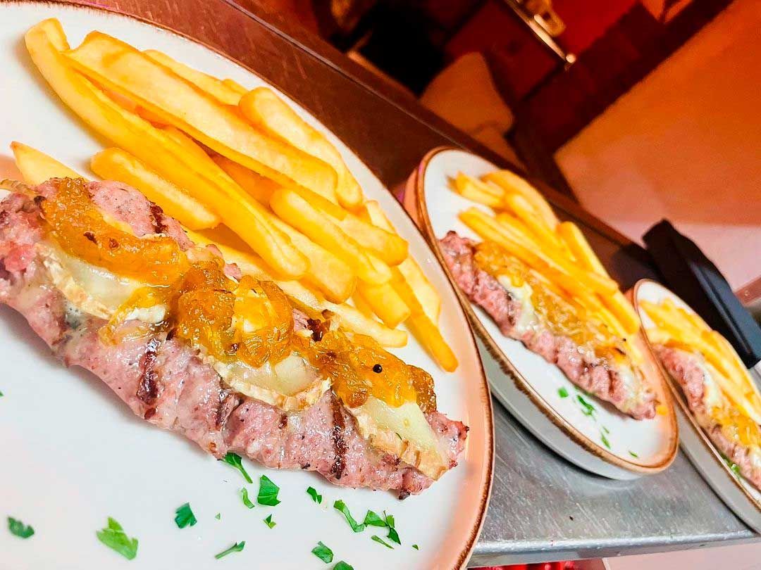Un plato blanco cubierto con carne y papas fritas.