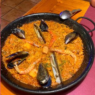 Una olla de comida con camarones, mejillones y arroz.