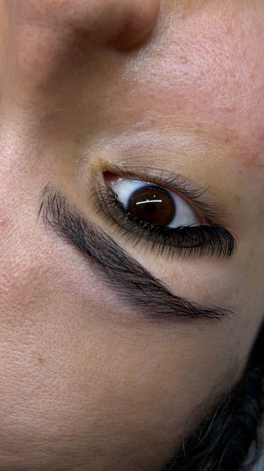 Primer plano de un rostro de perfil con un ojo abierto y un delineador de ojos negro intenso sobre un fondo pálido.