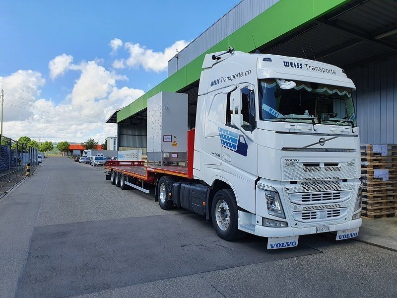 Ein weisser Sattelschlepper parkt vor einem grünen Gebäude. Foto von der Weiss Transporte AG.