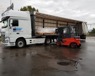 Ein Lkw und ein Gabelstapler stehen nebeneinander auf einem Parkplatz. Foto von der Weiss Transporte AG.