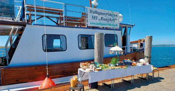 An einem Dock liegt ein Boot, davor steht ein Tisch.