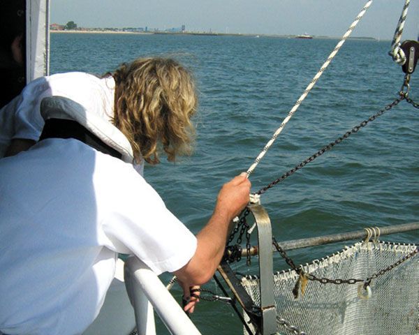Ein Mann zieht auf einem Boot im Meer an einem Seil