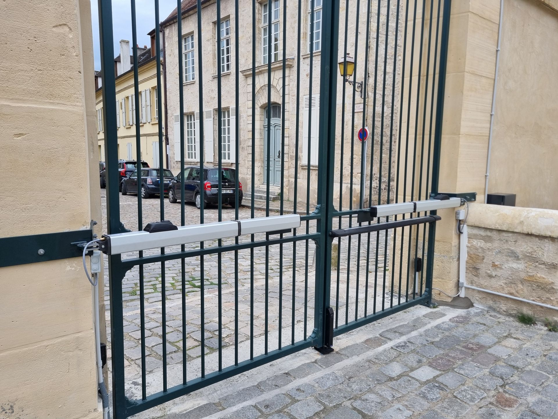 Portail métallique vert avec bras automatiques.