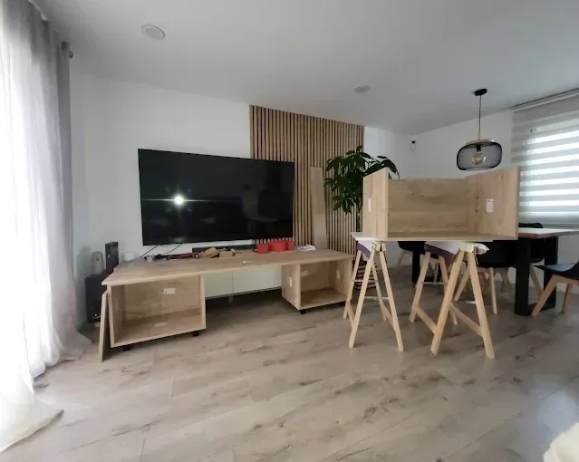 Una sala de estar con un televisor grande sobre una consola de madera y un mueble de madera.