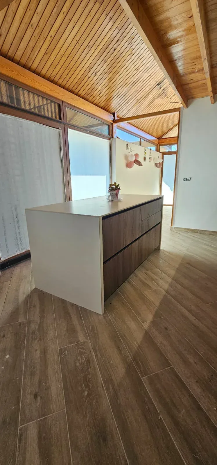 En una habitación luminosa y moderna, se encuentra una isla de cocina con encimera y armarios de madera.