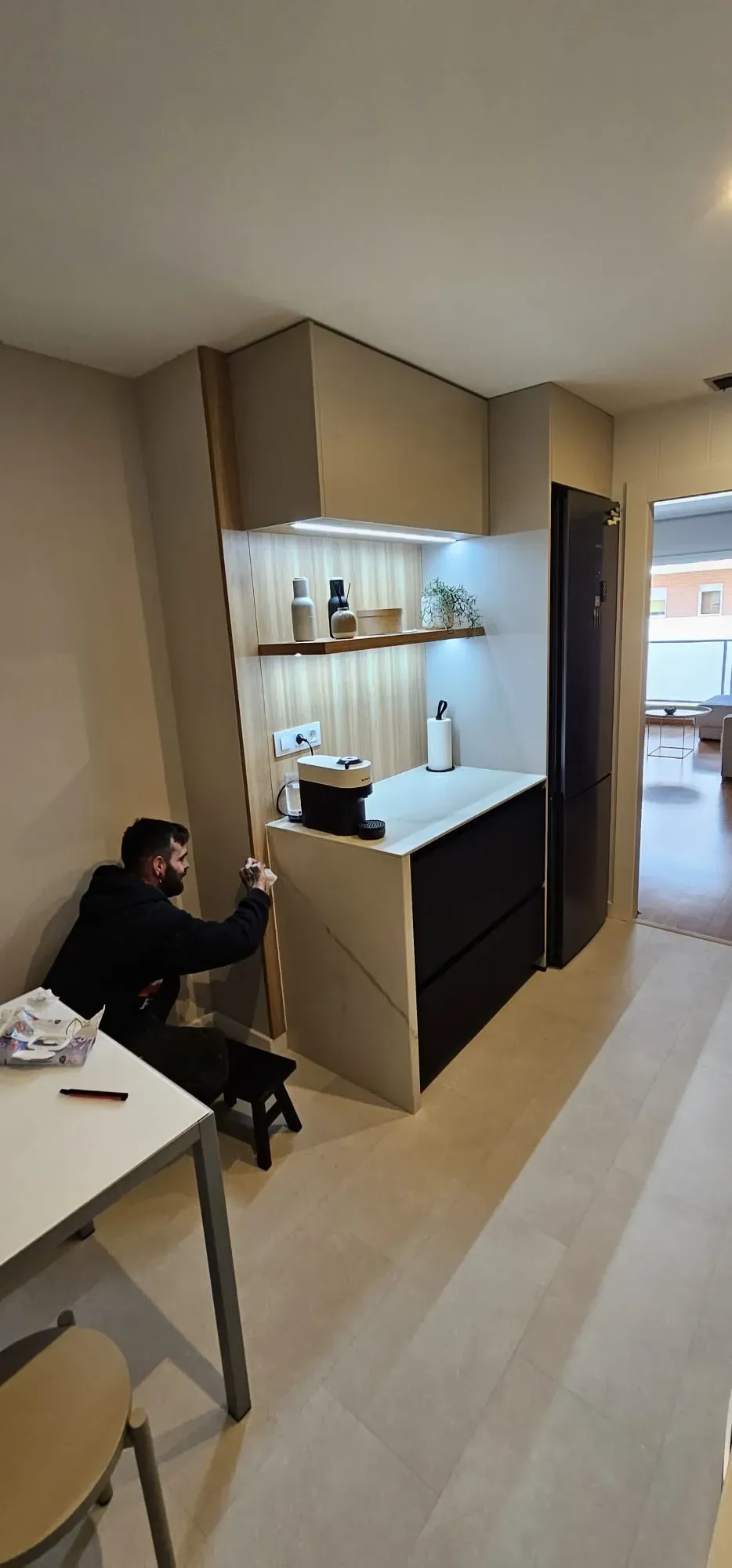 Trabajando en un mueble de cocina de madera hecho a medida, con iluminación integrada y encimera blanca.