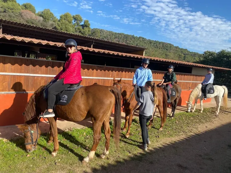 Un grupo de personas montan a caballo en un establo.